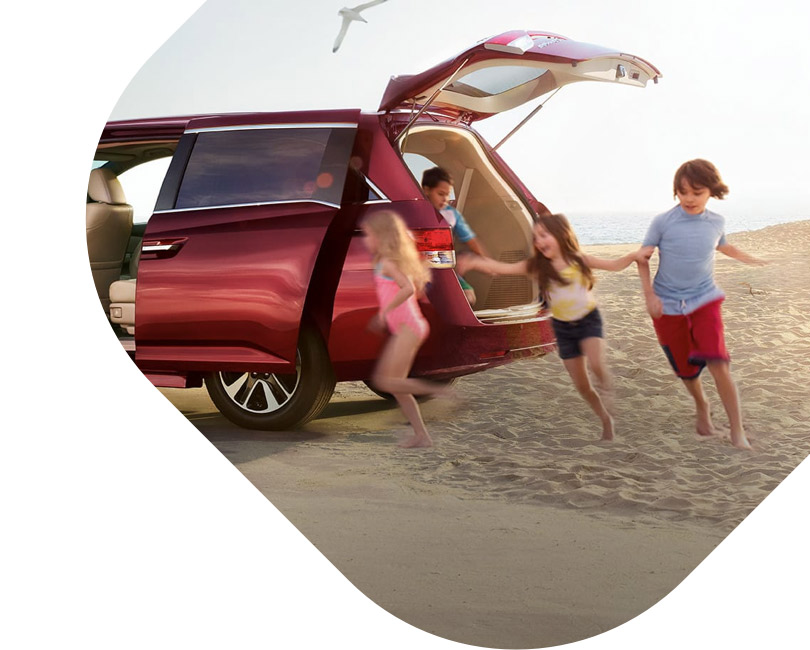 A family running onto the beach from their red van. 