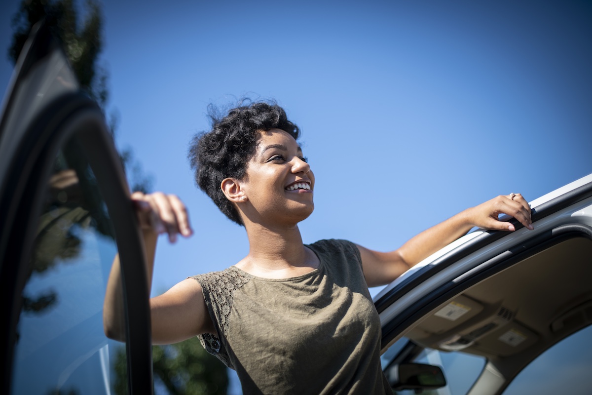 A woman smiling while exiting her used car. 