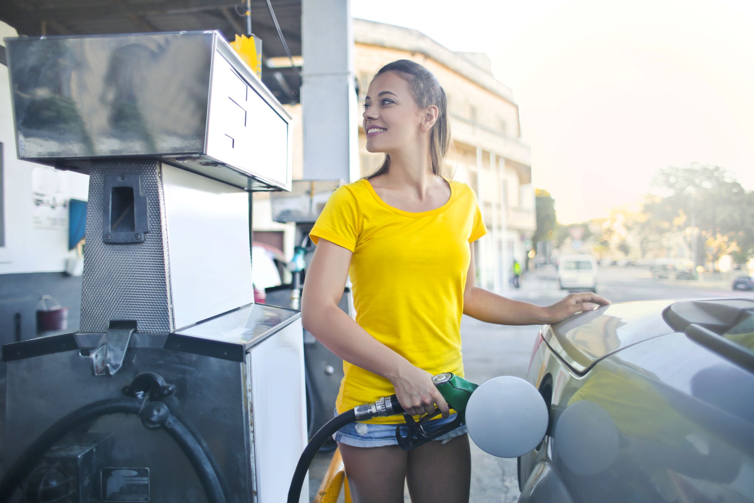A woman pumping gas into her used vehicle. 